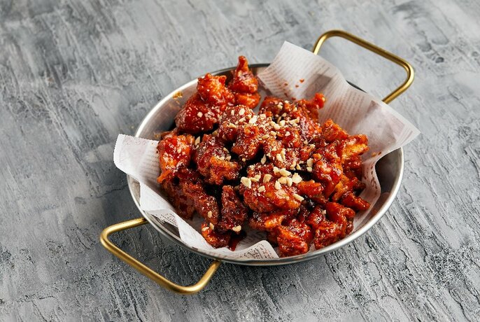 A bowl of Korean-style fried chicken coated in red sauce