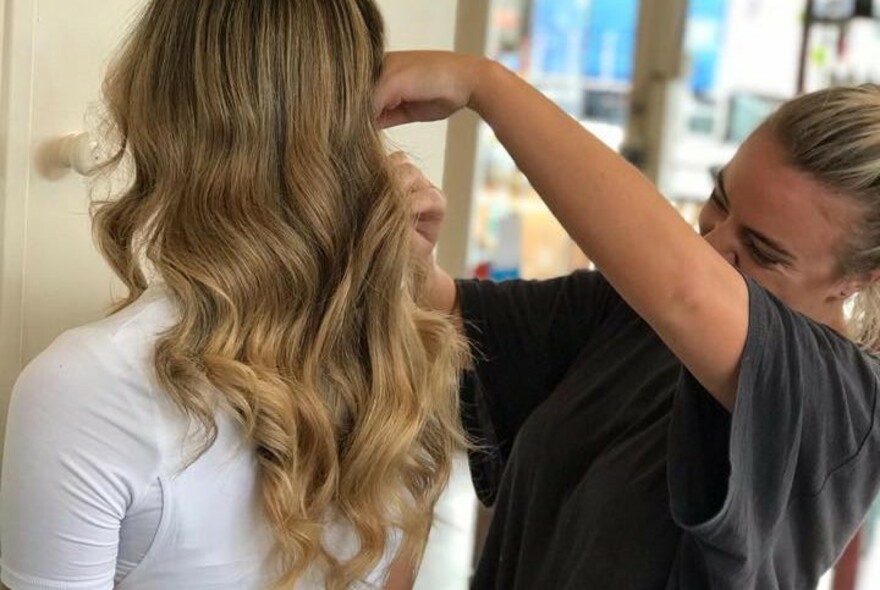Hairdresser brushing through the curly hair of a client. 