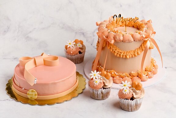 A selection of pink and orange cakes and cupcakes.