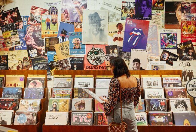 a woman standing in front of and looking at a vinyl record display 