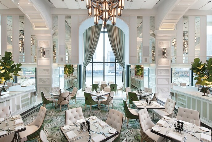 Light and bright interior with white seating and chandeliers.