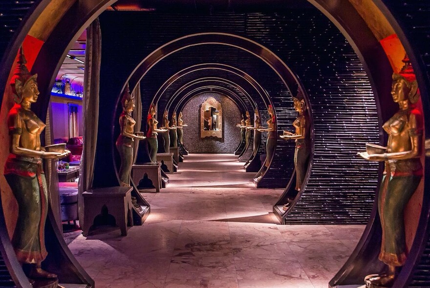 Hallway in lounge area of the bar showing gold coloured exotic statues in archways.