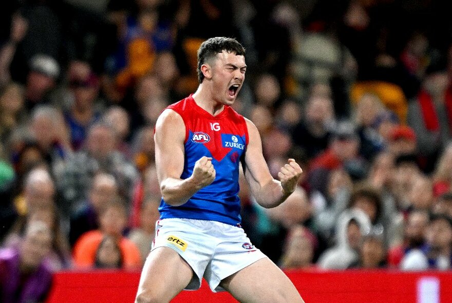 Melbourne AFL football player clenching fists and yelling during a match.