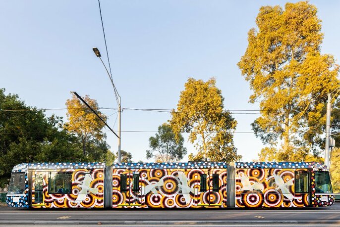 Melbourne tram decorated in Indigenous artwork of cockatoos with ochre and brown circles.