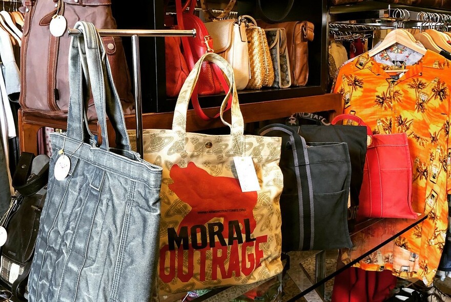 Vintage pre-loved luxury-brand fashion bags, handbags and tops hanging in a store.