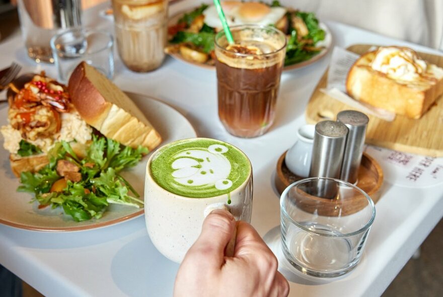A matcha drink with latte art and a sandwich