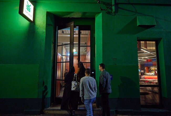 A group entering a restaurant in a bright green building.