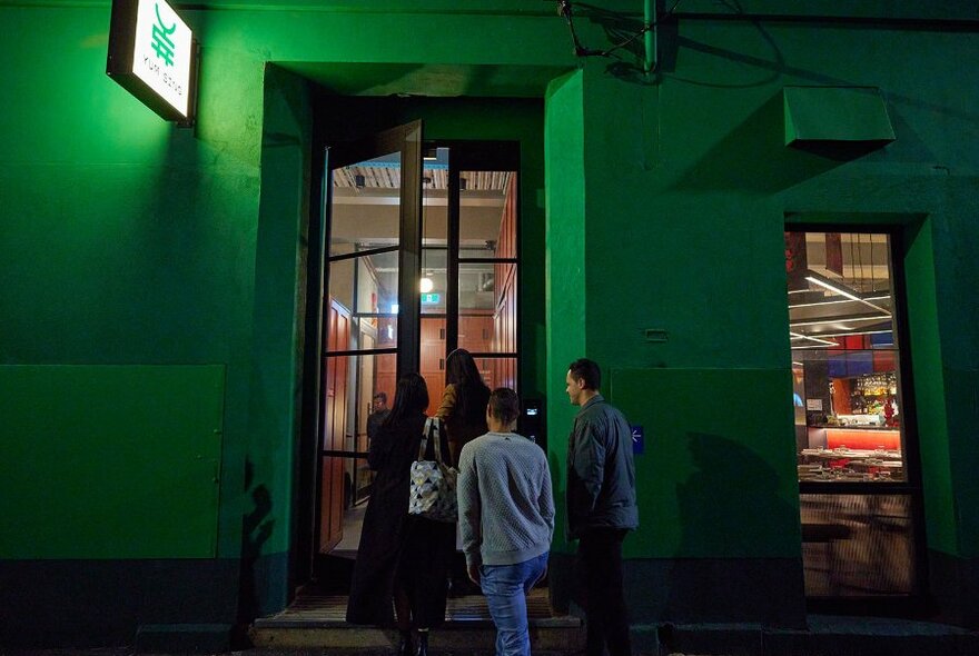 A group entering a restaurant in a bright green building.