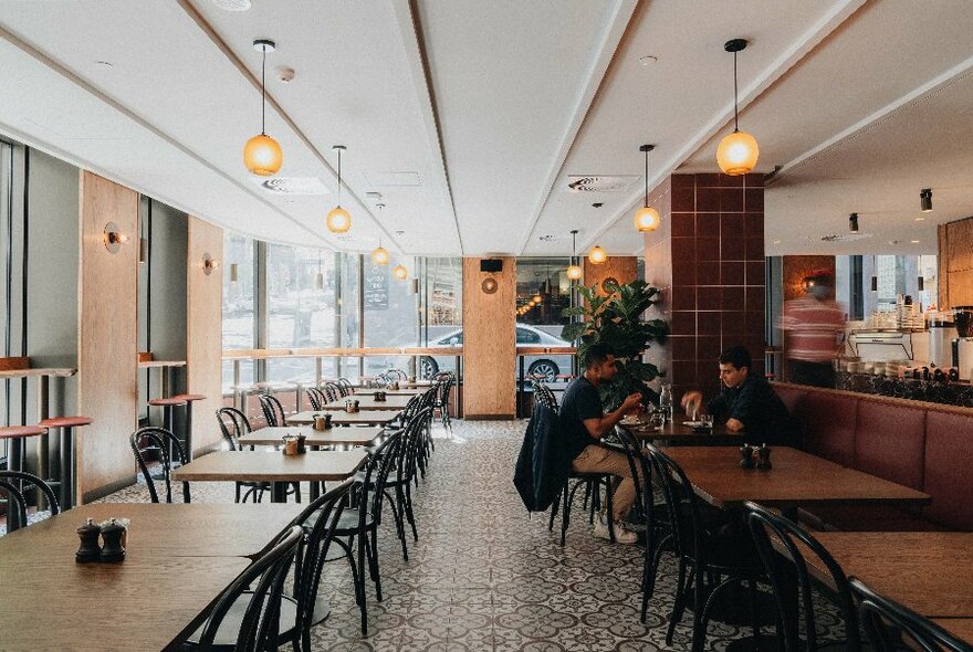 Interior of Rustica cafe with long rows of tables and chairs, patterned tiled floor and hanging lights.