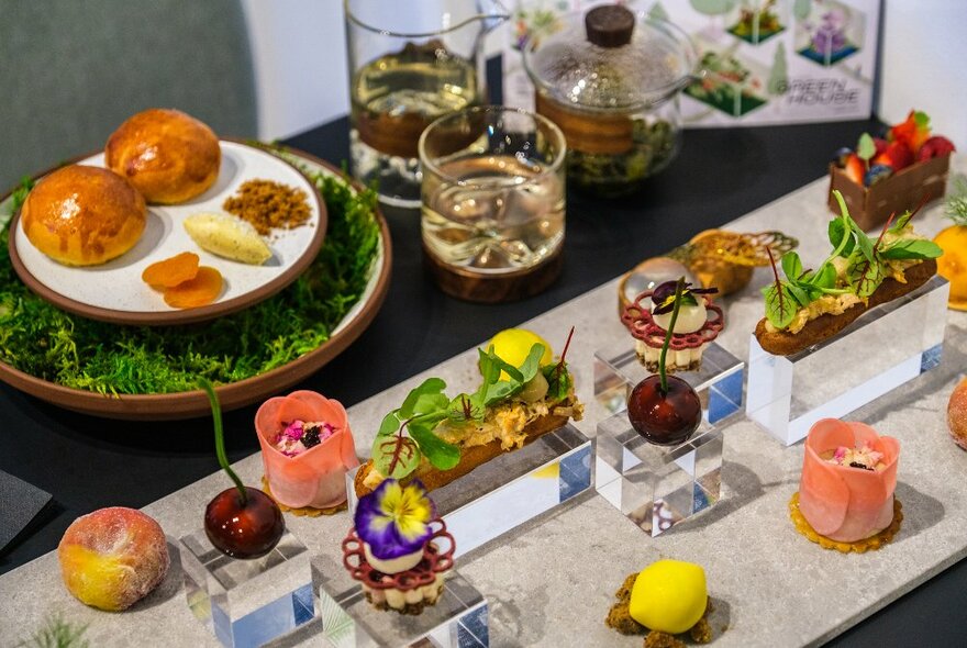 A table set with high tea dishes shaped like fruits and flowers.