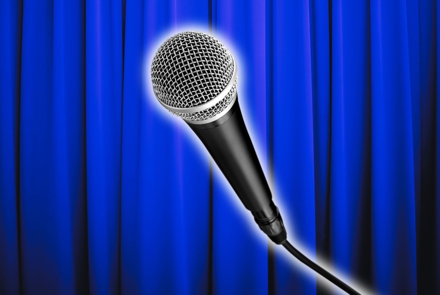 A backlit microphone with a deep blue curtain behind.