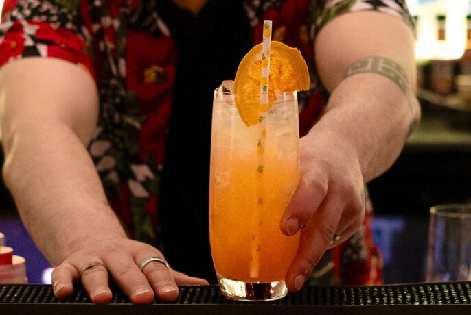 Bartender serving an orange cocktail.