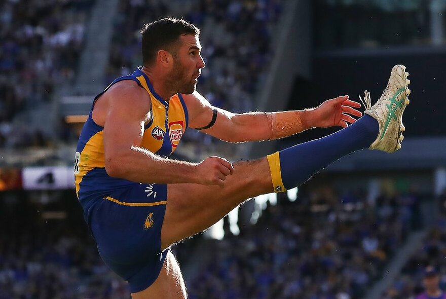 West Coast Eagles AFL football player kicking his leg in the air during a match.