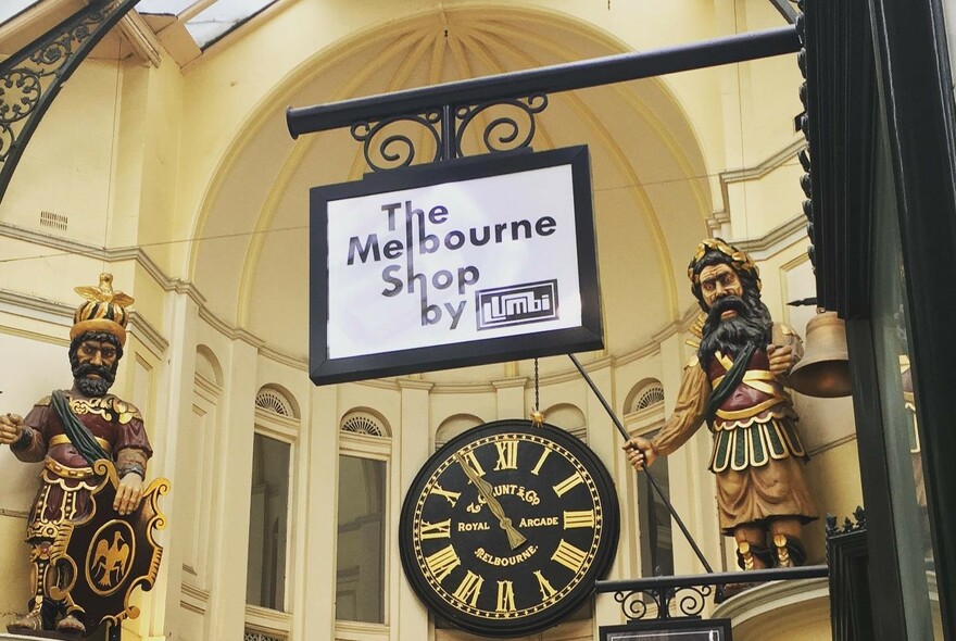 Gog and Magog statues in Royal Arcade with shop signboard.