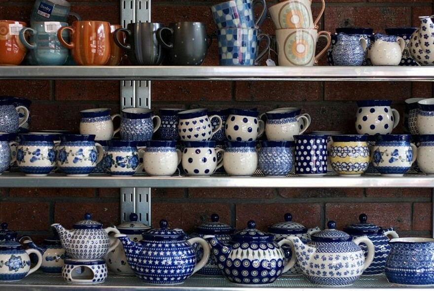 Display of blue and white ceramic teapots and mugs. 