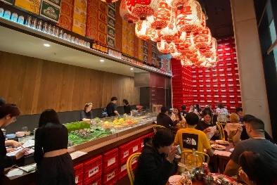 A crowded Thai eatery with tables close to a display of food. 