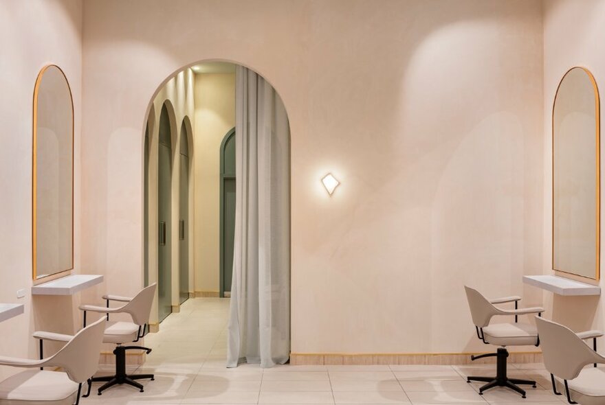 Salon interior with curtained arched doorway, pale pink decor and furnishings.