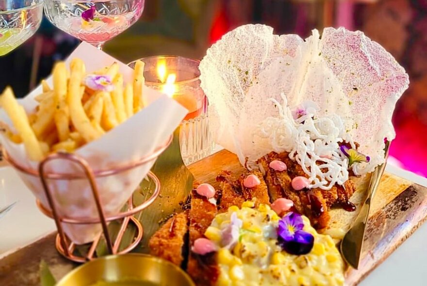 A gold tray of food including chips in paper wrapping and lacy crisps.