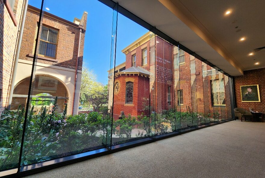 Looking out through floor to ceiling glass windows onto buildings around a courtyard, part of the Mary MacKillop Heritage Centre.