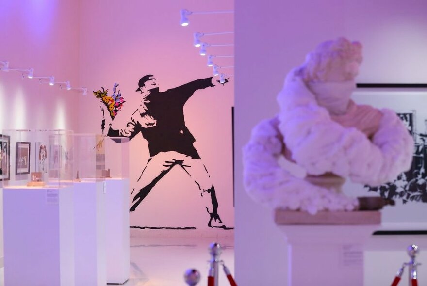 Banksy artworks displayed in a gallery, including stencil paintings on the wall
