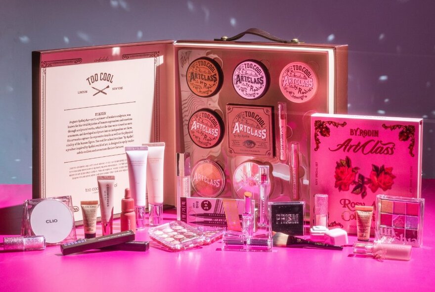 A range of skincare and cosmetics arranged on a pink table with large display boxes in the background
