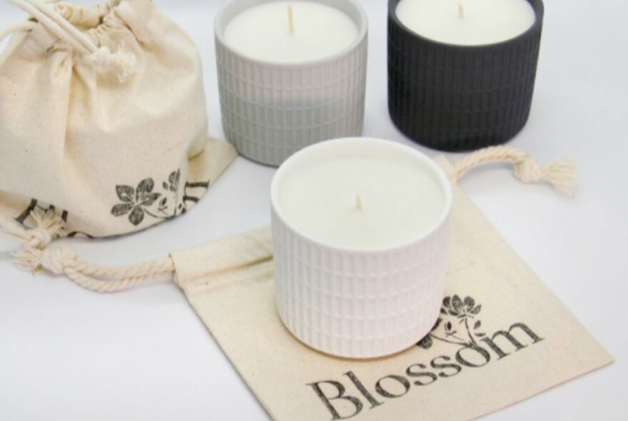 Three candles, one sitting on a calico bag that says Blossom.