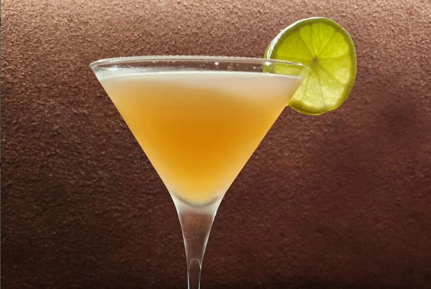 A cocktail with a slice of lime as garnish.