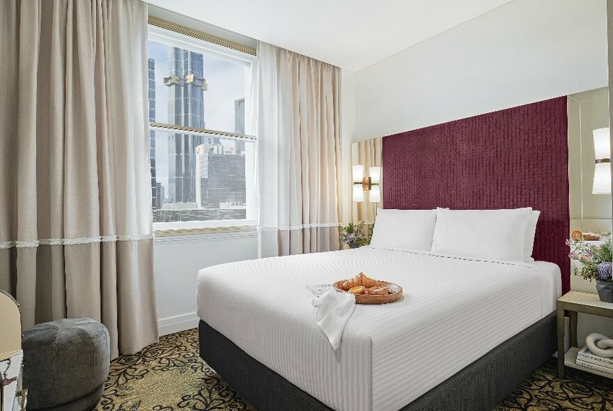 A deluxe room at the Rendezvous Hotel Melbourne overlooking the city skyline.