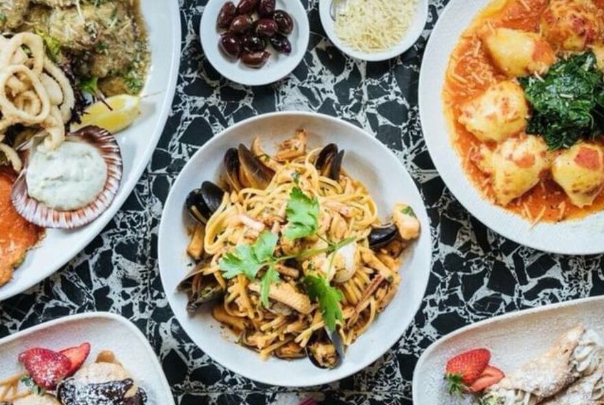 A selection of traditional Italian dishes, with linguine marinara in the centre.