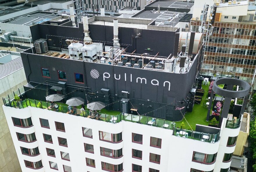 Looking down at a rooftop garden  on top of a city building with the word Pullman across the top. 