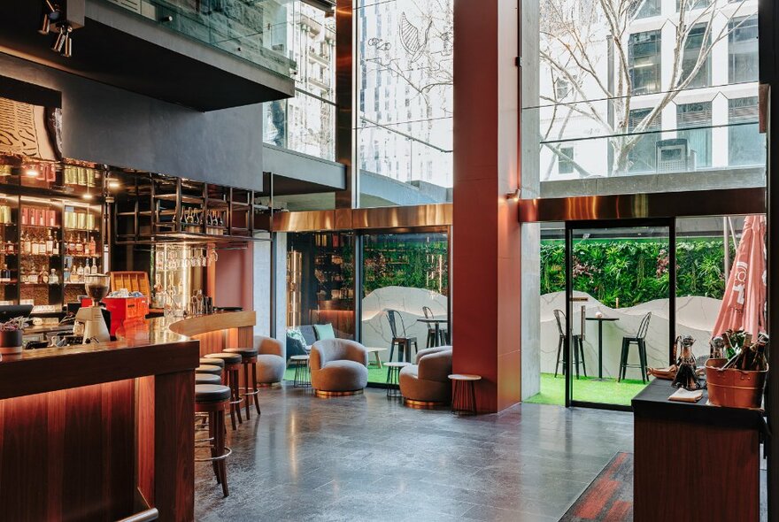 The interior of a bar with huge floor to ceiling windows and concrete floor.