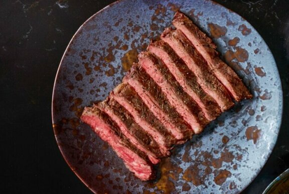 Finely sliced medium-rare Wagyu steak arranged on dinner plate.