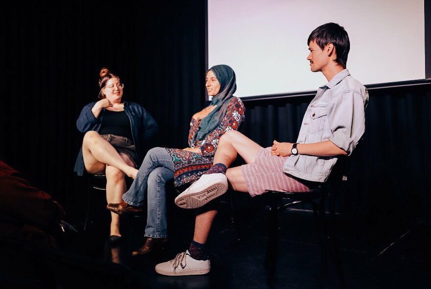 Three people seated on a stage in an interview situation.