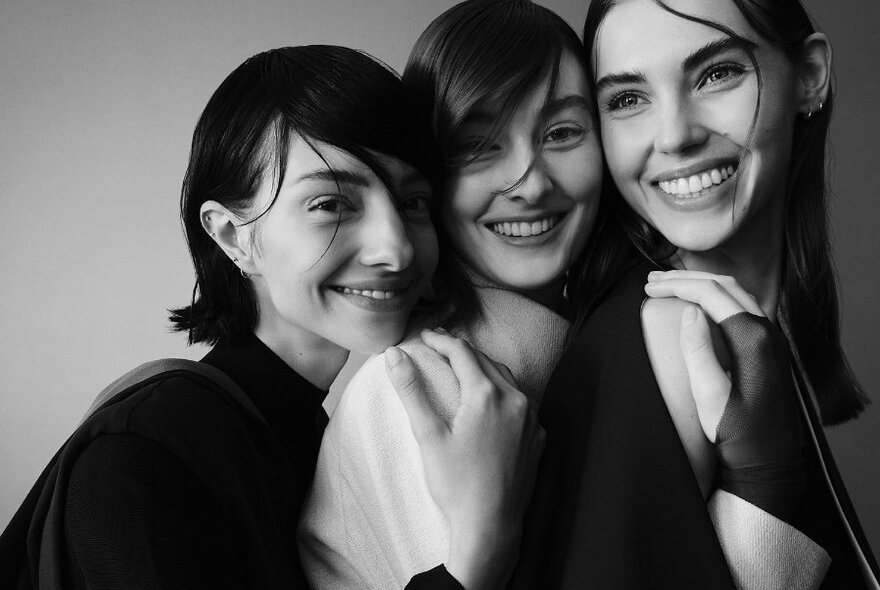 Black and white of three young woman cuddling together.