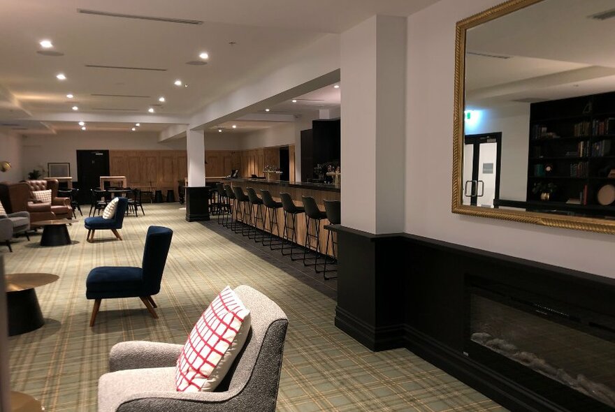 A hotel bar with bar seating and armchairs 