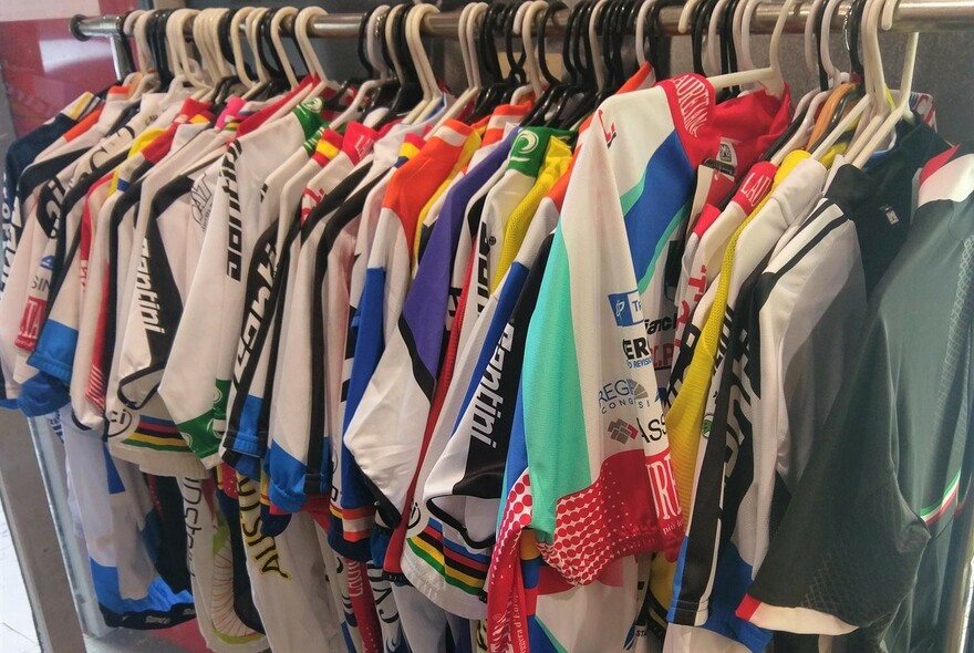 Clothing rack with many lycra cycling tops hanging off hangers.
