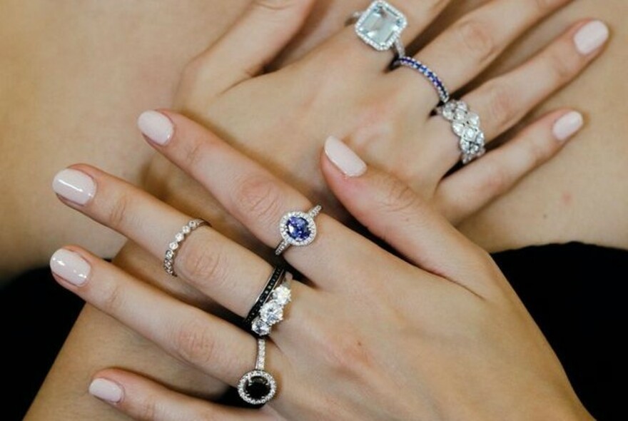 A model's hands with rings on each finger, with diamonds and precious stones.