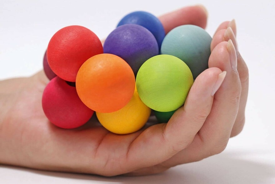 Hand holding a number of small, coloured balls.