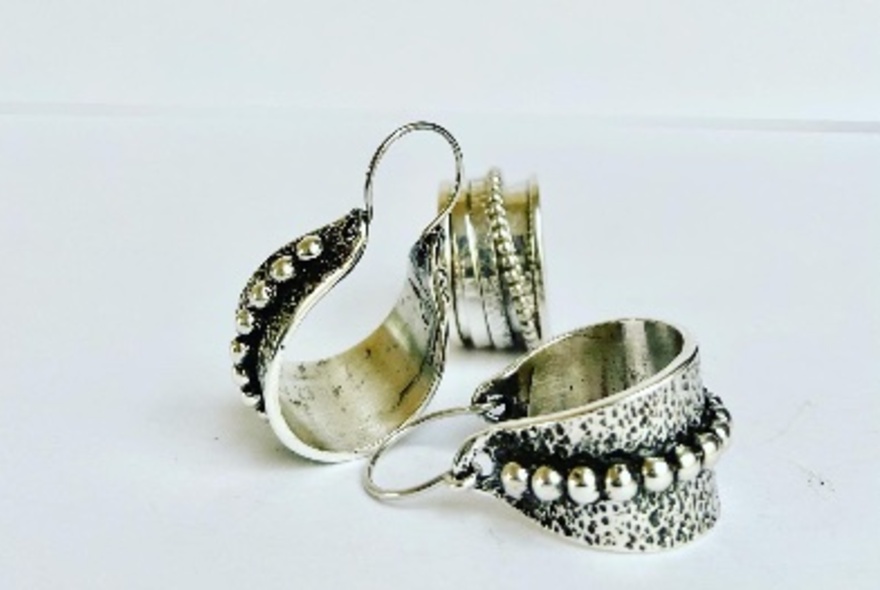 Contemporary silver earrings and a silver ring displayed on a white background.