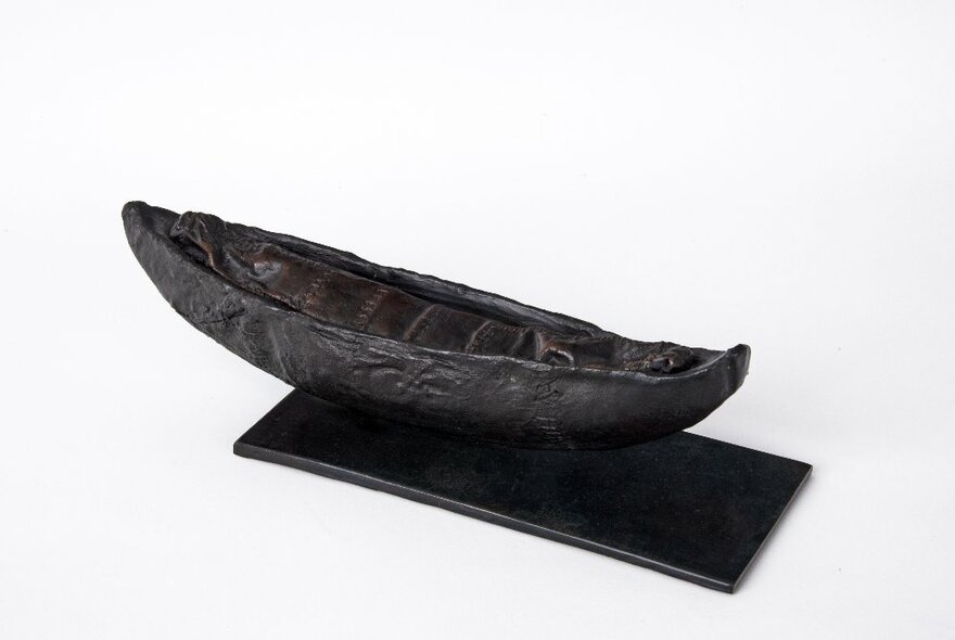 A black canoe-like sculpture in a white space.