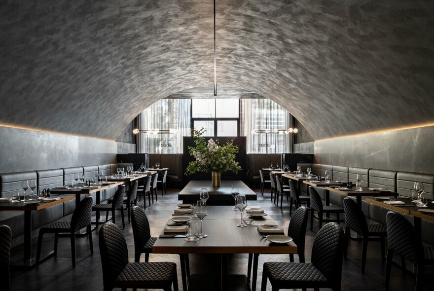 Vault-like dining setting with banquettes and tables set for dinner.