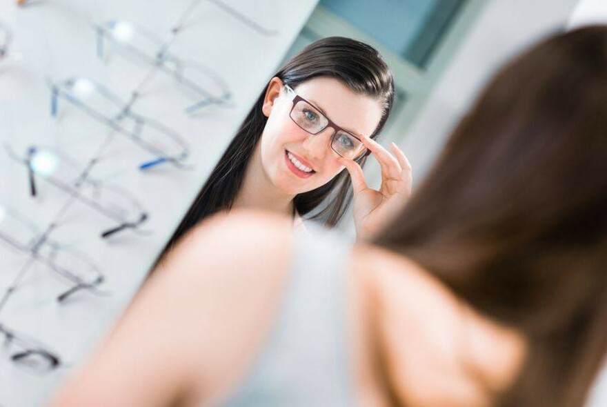 Person trying on glasses an looking at themselves in a mirror.