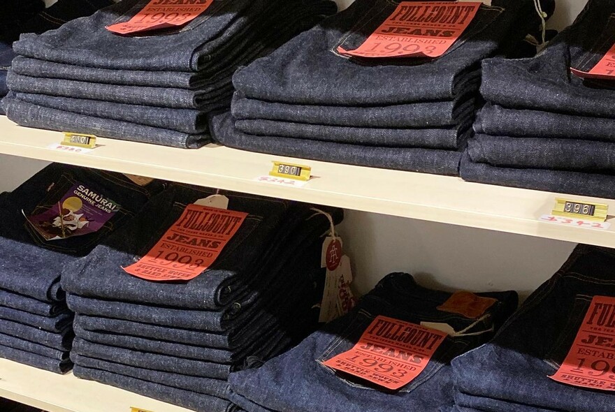 Pairs of jeans folded on shelves in a store.