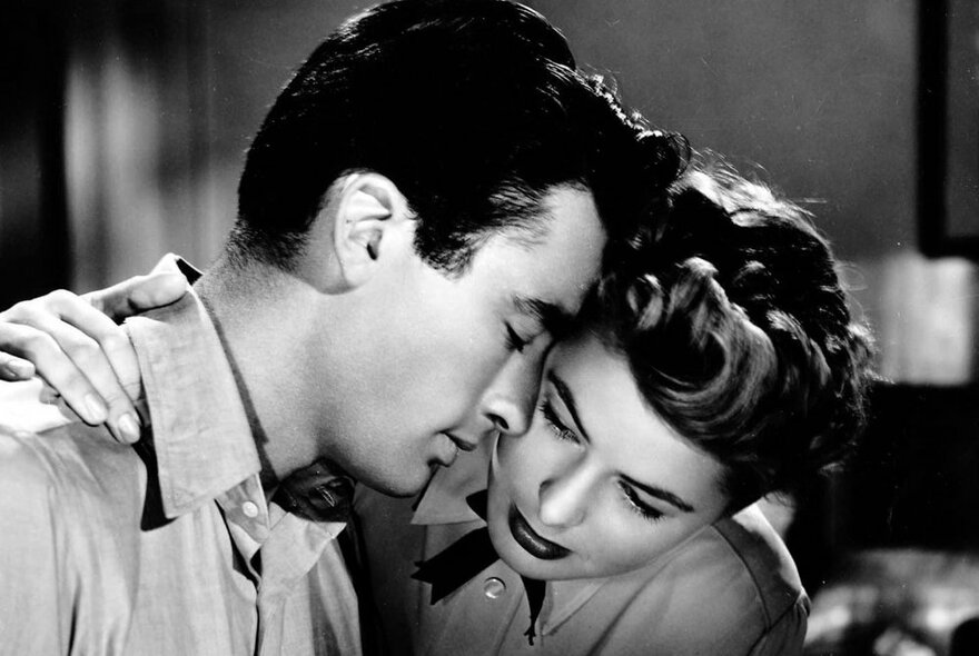 Still from a movie with two Hollywood actors - Gregory Peck and Ingrid Bergman - with their heads touching in an affectionate pose; black and white 1950s style.