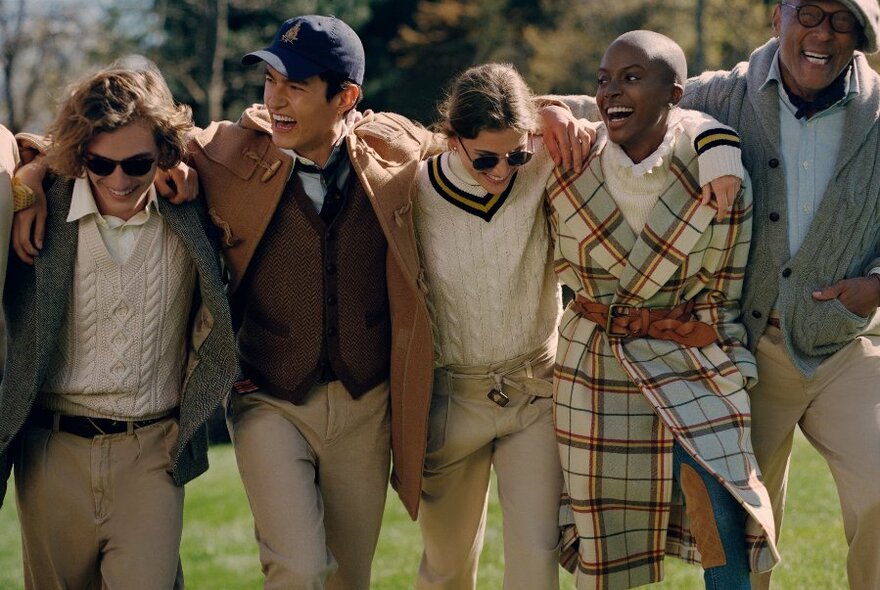 Five people all wearing Polo Ralph Lauren clothing, walking outdoors with arms linked over each other's shoulders.